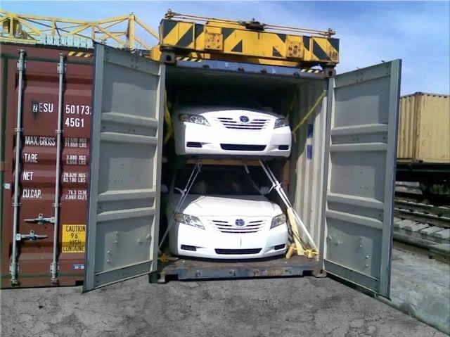 Vehicles being loaded into shipping containers